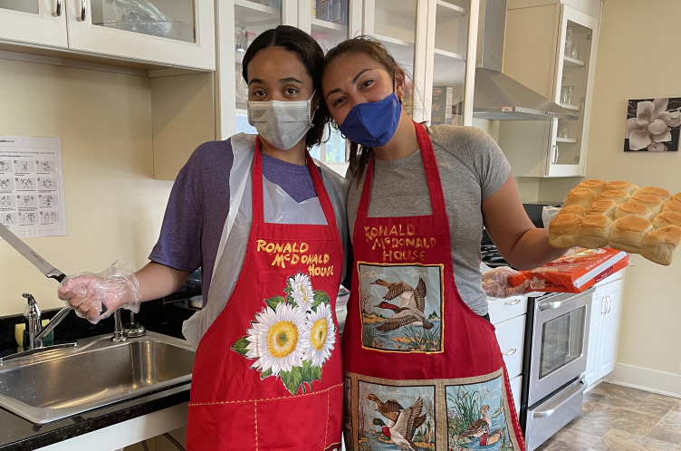 Two student volunteers at the Ronald MacDonald House prepare a meal for guests at the house, who stay there while their children are in the hospital.