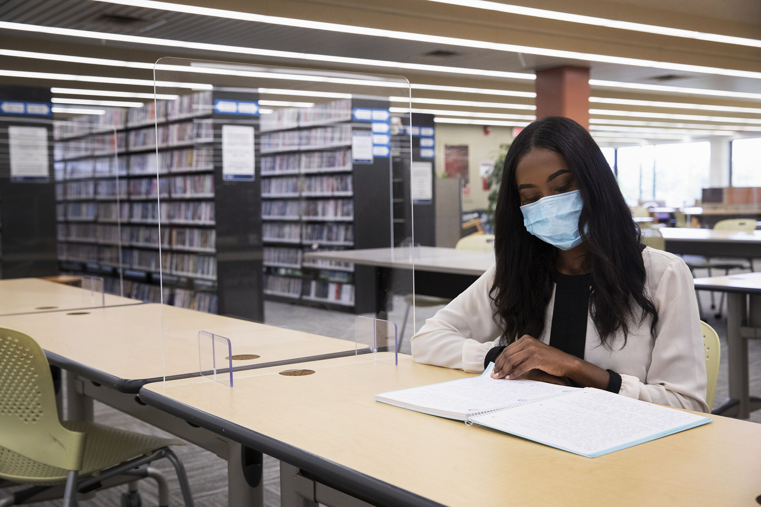Rachel Jeffers studies in Clemons Library, which, along with the Charles L. Brown Science and Engineering Library, is open to students, with study spaces marked off by signs and clear plastic dividers.
